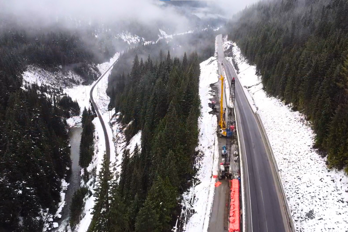 Road jobsite from above surrounded by snow and green pine trees