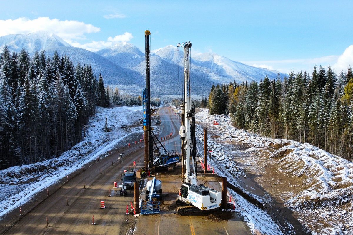 Road jobsite from above with two cranes and the mountains in the background