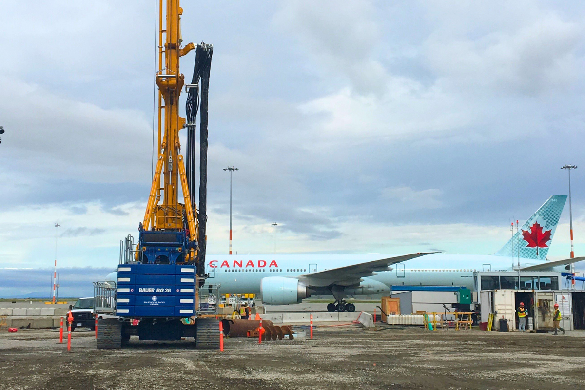 a crane next to a white airplane with CANADA written on it in red