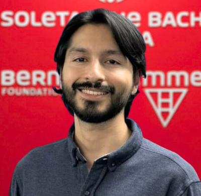 Photo of David Ospina in SBC's office with a red background and the Soletanche Bachy Canada and Berminghammer logos