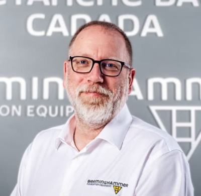 Photo of Steve England in SBC's office with a gray background and the Soletanche Bachy Canada and Berminghammer logos