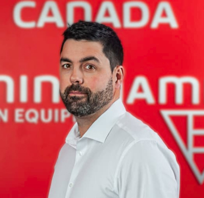 Photo of Tom Humphries in SBC's office with a red background and the Soletanche Bachy Canada and Berminghammer logos