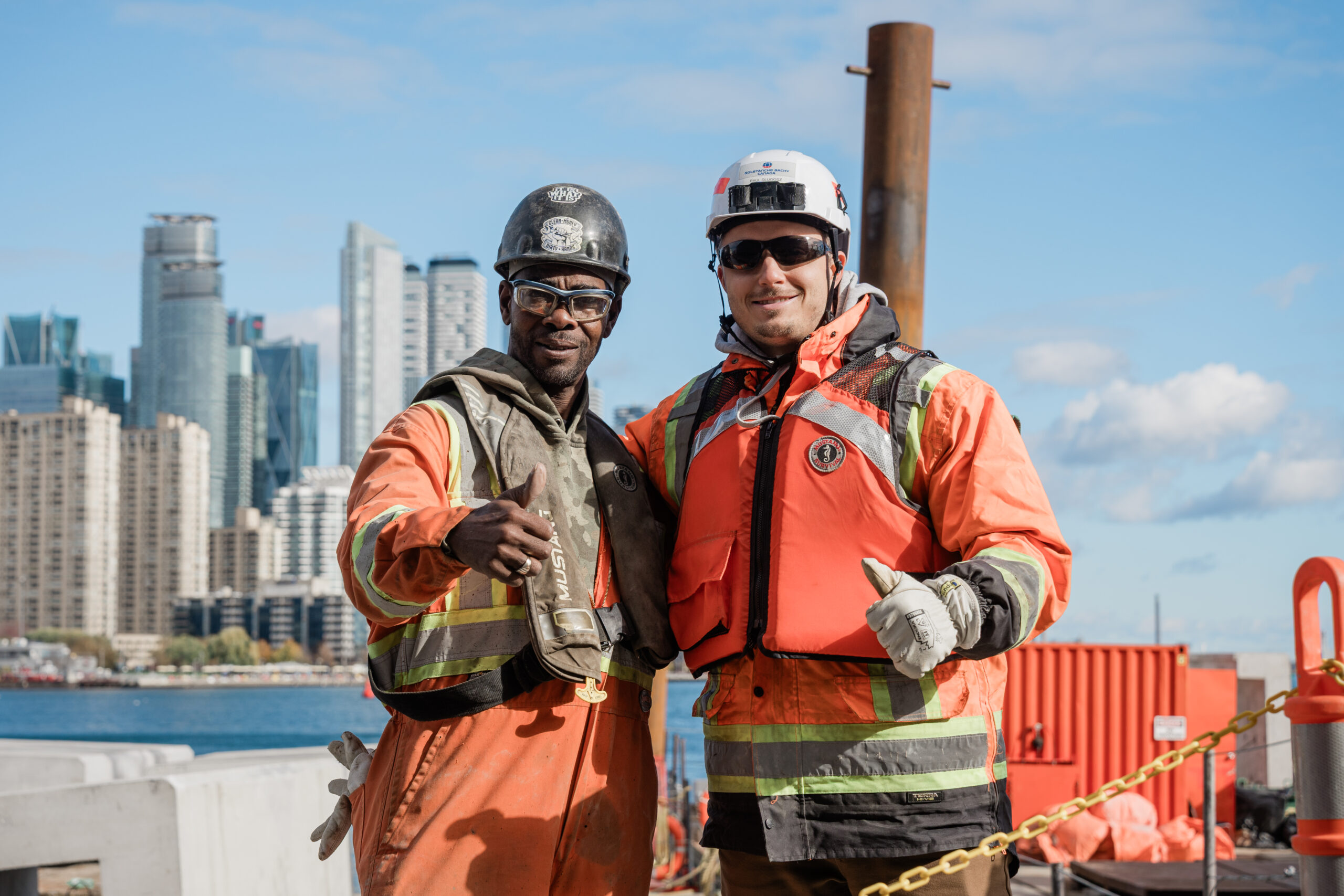 BillyBishop-53 two workers on a jobsite facing the camera and smiling with the thumbs up