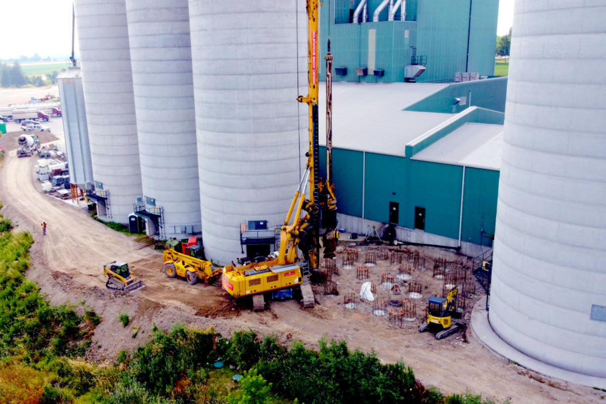 Jobsite next to an industrial building with big gray cylinder containers