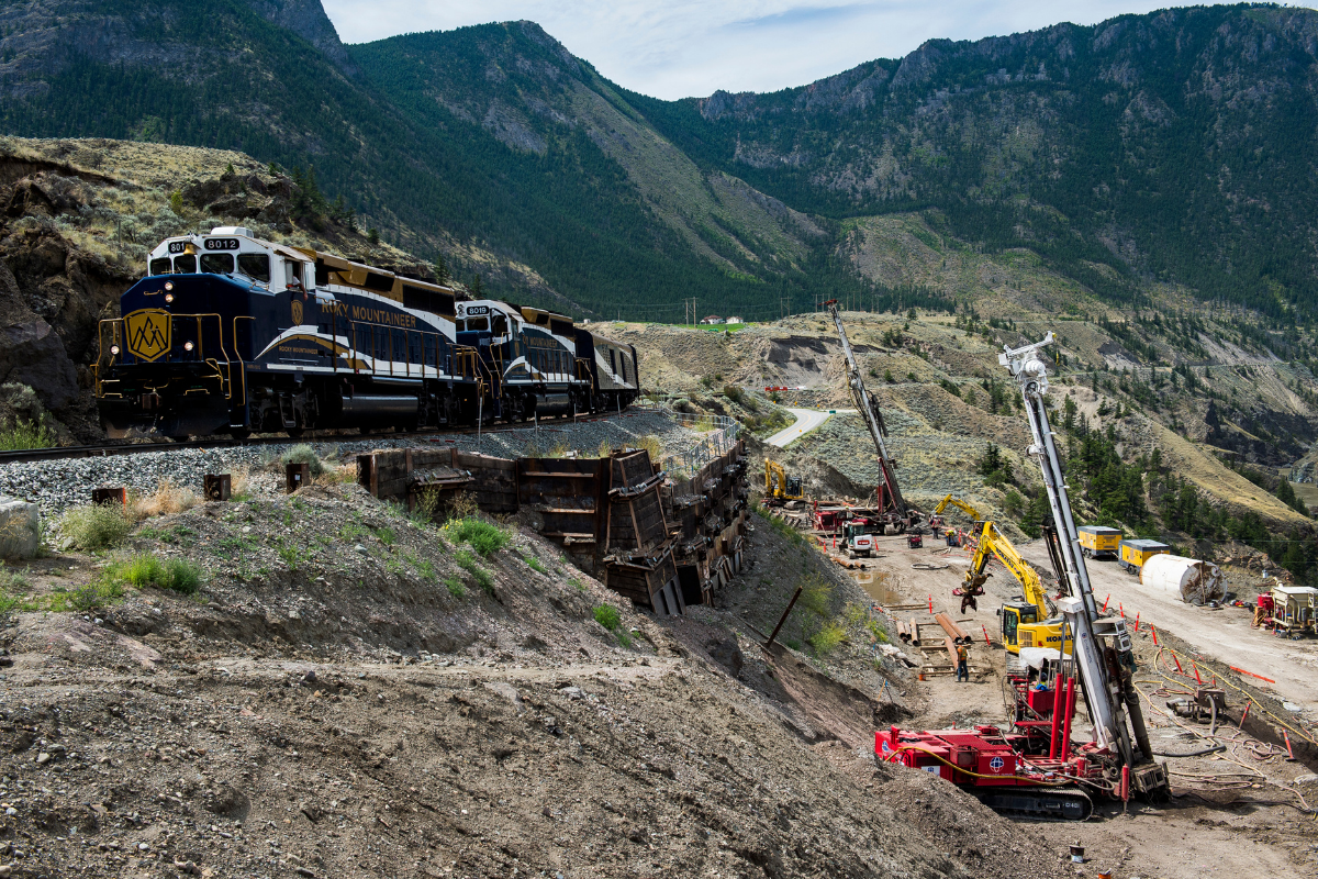 jobsite next to a railway in the mountains with a train passing