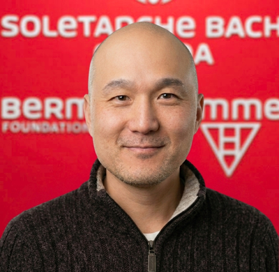 Photo of Nicholas JIN in SBC's office with a red background and the Soletanche Bachy Canada and Berminghammer logos